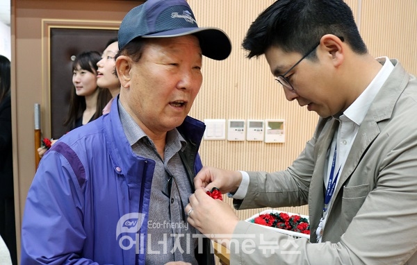 한국동서발전 직원(오른쪽)이 어버이날 행사에 참여한 어르신께 카네이션을 달아드리고 있다.