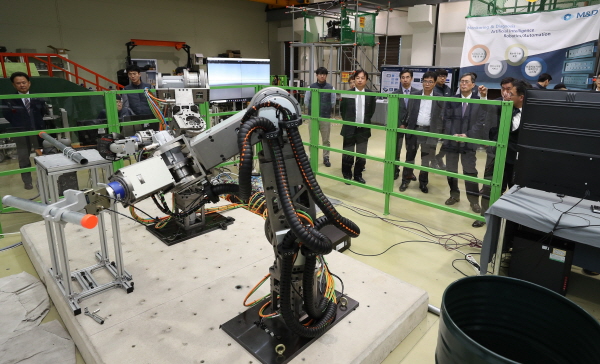 정재훈 한수원 사장이 13일 국산화 기술 개발 협약을 체결한 방화댐퍼 시험용 로봇팔을 보고 있다