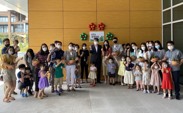 8월 3일 에너지공단 본사에서 진행된 ‘동행텃밭’ 조성 행사에 참석한 김창섭 한국에너지공단 이사장(현판 앞 회색 정장) 및 사내어린이집 원생과 가족들이 행사 후 기념촬영을 하고 있다.